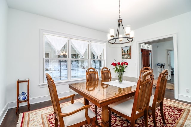 dining space featuring baseboards, dark wood-style flooring, and an inviting chandelier