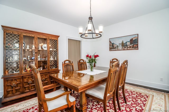 dining room featuring a chandelier, baseboards, and wood finished floors