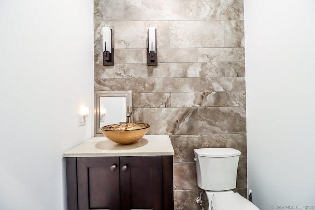 bathroom with toilet, tile walls, and vanity