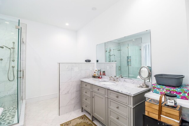 bathroom with a stall shower, marble finish floor, tile walls, and vanity