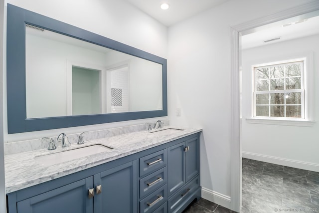 bathroom with double vanity, baseboards, visible vents, and a sink