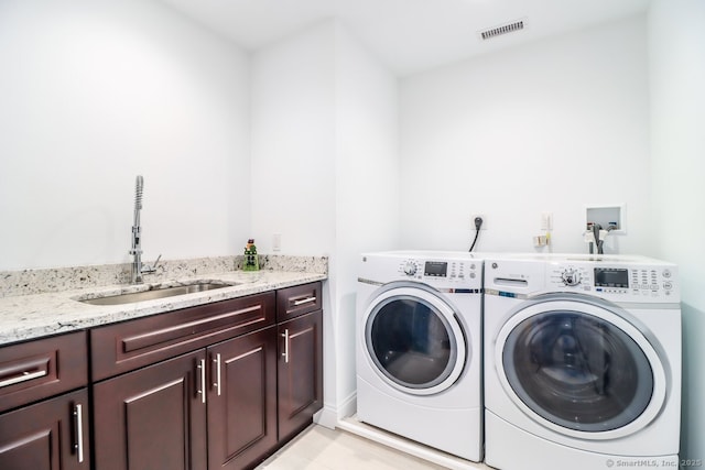 laundry room with cabinet space, visible vents, a sink, and washer and clothes dryer