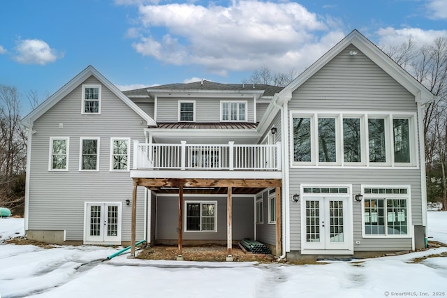 snow covered property with french doors and a wooden deck