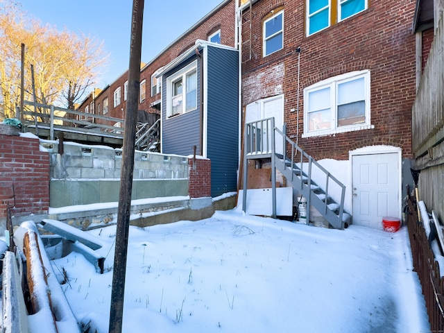 snow covered property with brick siding