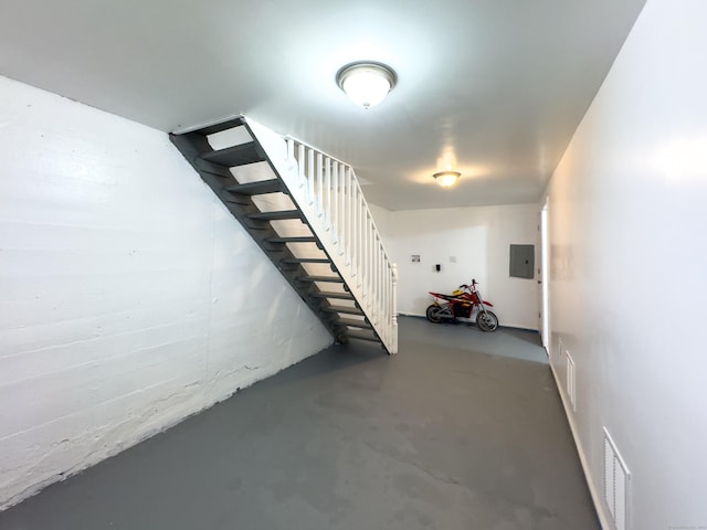 stairs featuring finished concrete flooring, electric panel, and visible vents