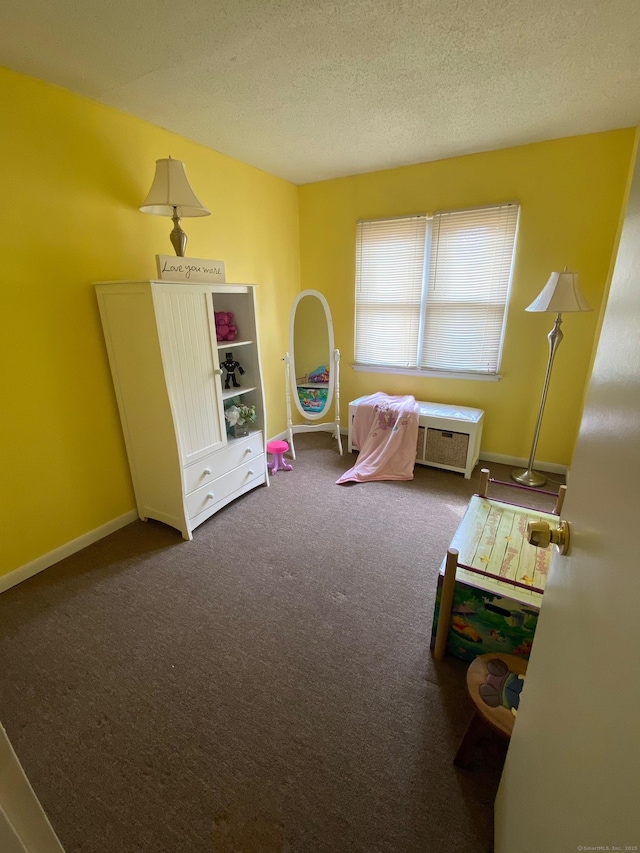 rec room featuring a textured ceiling, carpet flooring, and baseboards