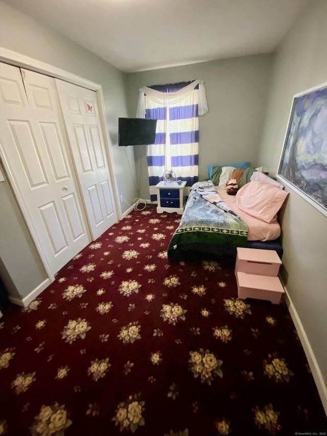 carpeted bedroom with a closet and baseboards