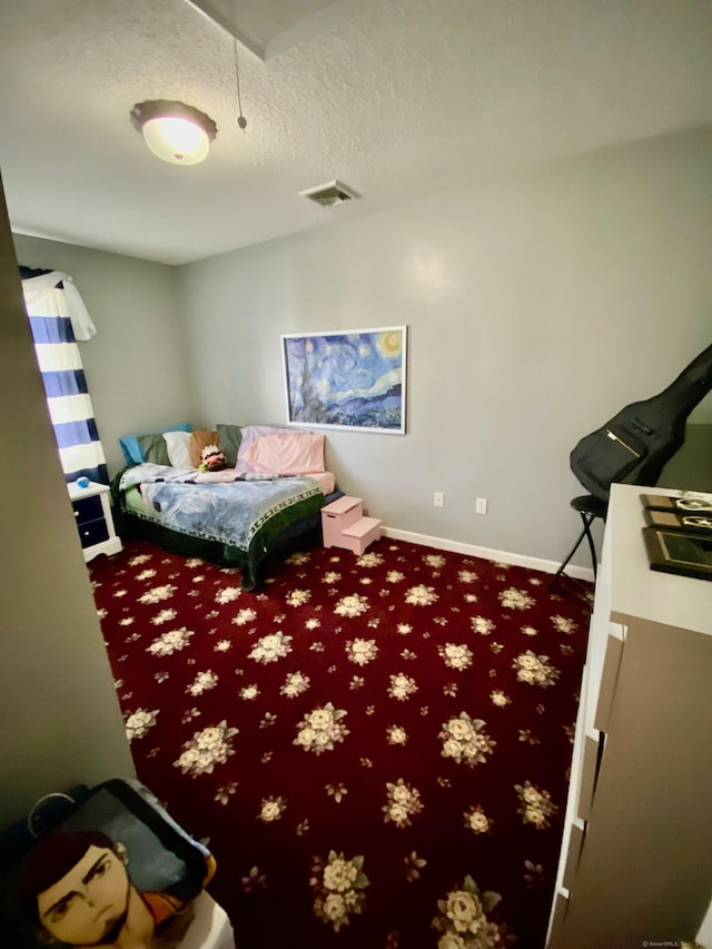 bedroom with attic access, baseboards, visible vents, a textured ceiling, and carpet floors