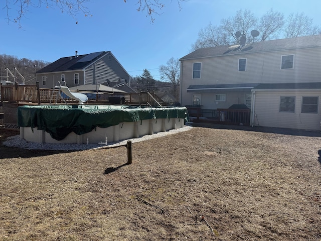 view of yard with a wooden deck and a covered pool