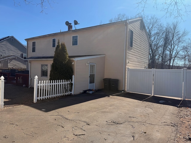 back of house featuring a gate and fence