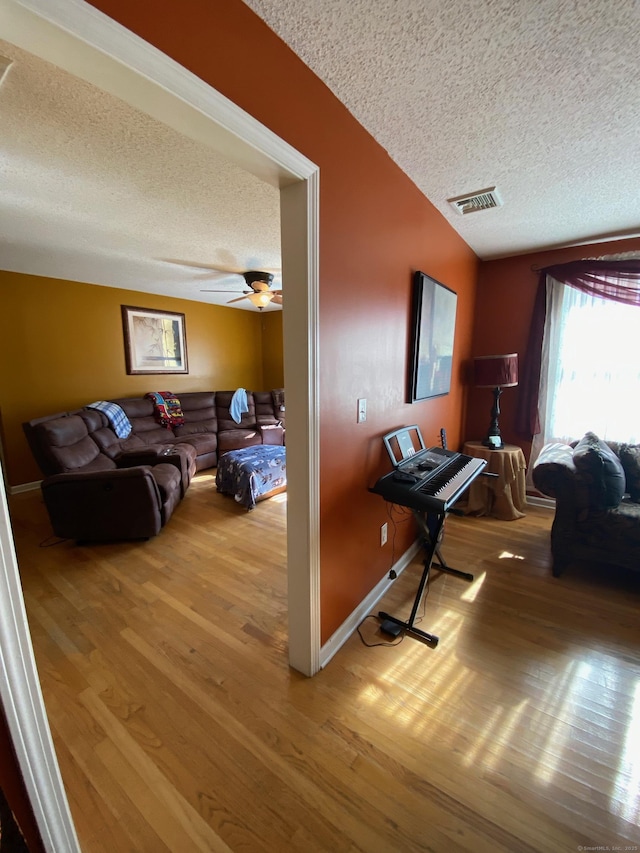 interior space featuring visible vents, vaulted ceiling, a textured ceiling, wood finished floors, and baseboards