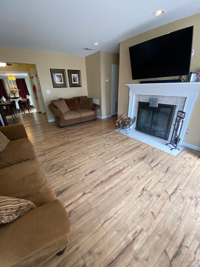 living room featuring a fireplace, baseboards, wood finished floors, and recessed lighting