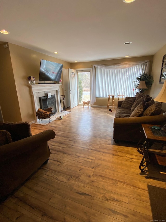 living room with recessed lighting, wood finished floors, and a tile fireplace