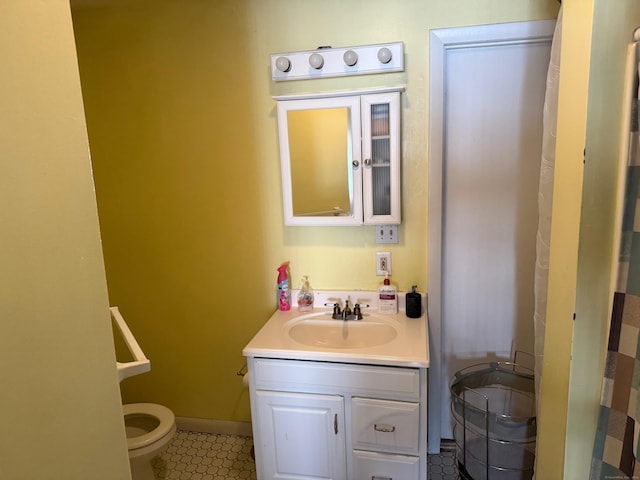 bathroom featuring baseboards, vanity, and toilet