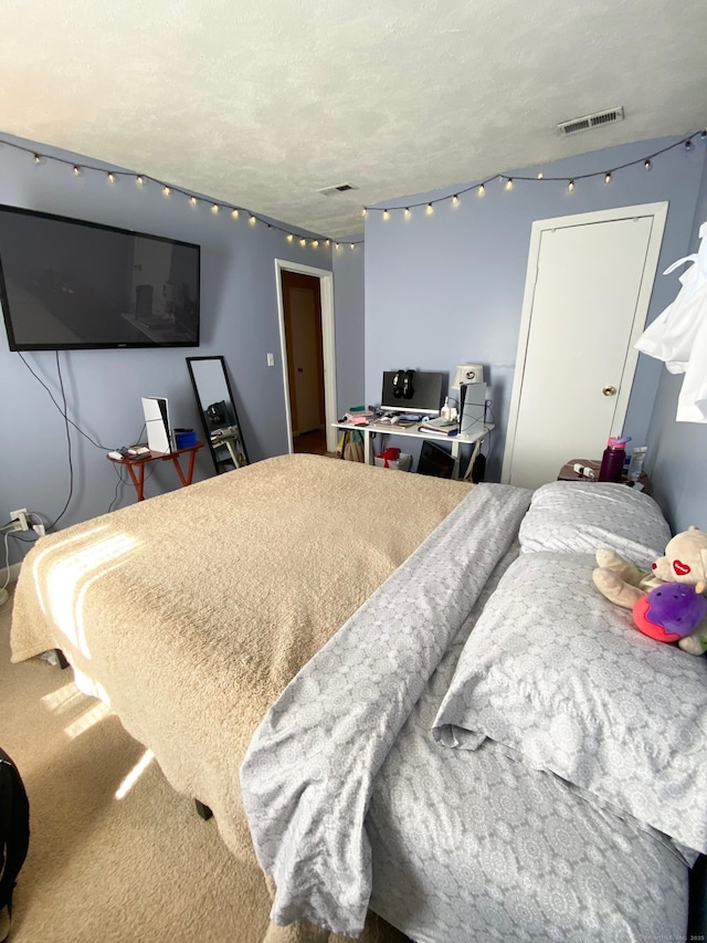 bedroom with a textured ceiling, visible vents, and carpet flooring