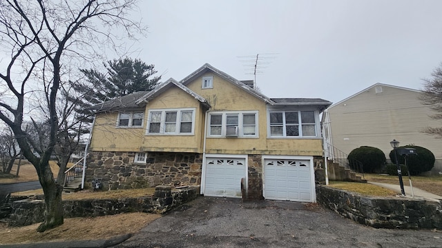 view of front of house with stone siding, driveway, stairway, and stucco siding