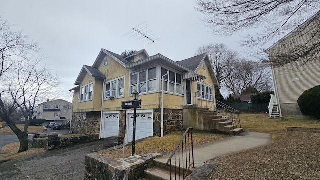 view of side of home featuring stucco siding, an attached garage, stone siding, driveway, and stairs