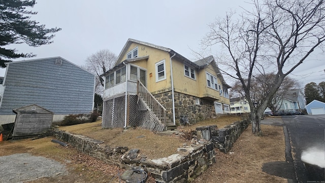 view of property exterior with stone siding, stairway, and stucco siding