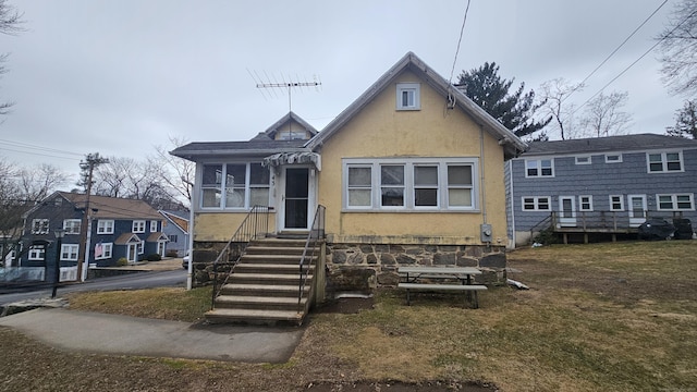 bungalow-style house with entry steps and stucco siding