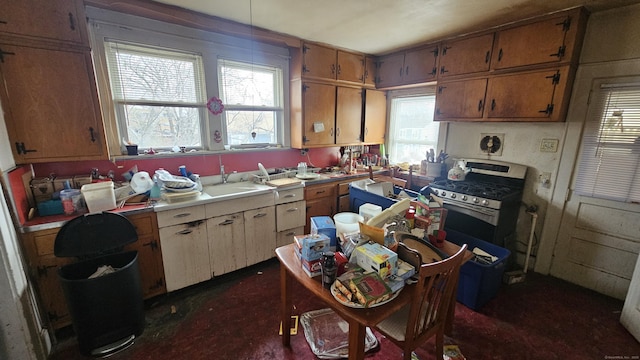 kitchen featuring light countertops, gas stove, a sink, and brown cabinets