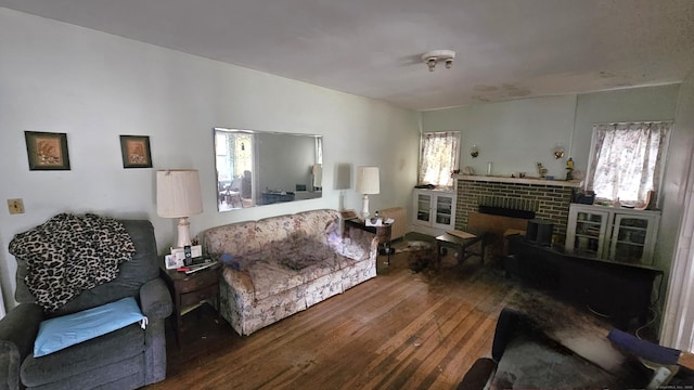 living area featuring a wealth of natural light, a brick fireplace, and hardwood / wood-style flooring