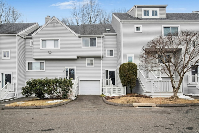 view of front facade featuring roof with shingles, driveway, and an attached garage