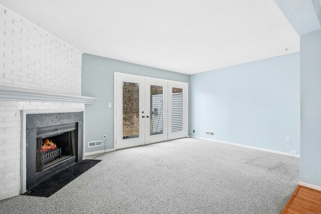 unfurnished living room with carpet, a high end fireplace, visible vents, and french doors