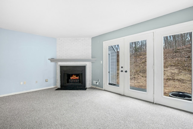 unfurnished living room with carpet, a brick fireplace, plenty of natural light, and baseboards