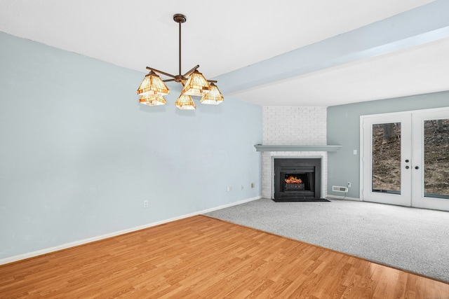 unfurnished living room with a fireplace, wood finished floors, baseboards, french doors, and beam ceiling