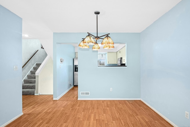 unfurnished dining area with baseboards, stairway, and wood finished floors