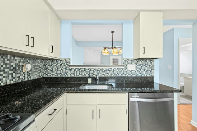 kitchen with decorative backsplash, appliances with stainless steel finishes, dark stone countertops, light wood-type flooring, and a sink