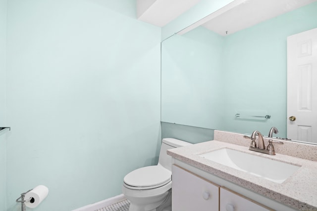 bathroom featuring toilet, tile patterned flooring, baseboards, and vanity