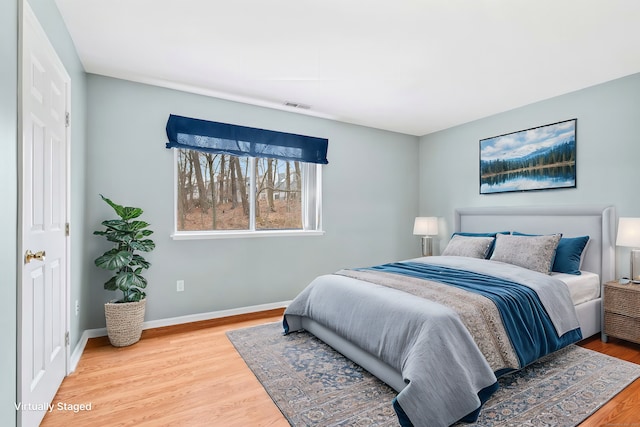 bedroom with baseboards, visible vents, and wood finished floors