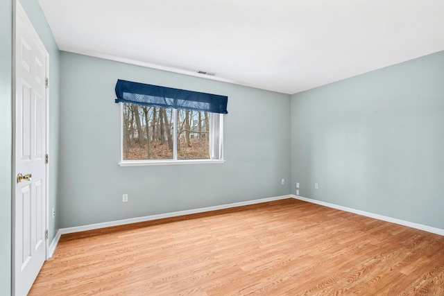 spare room with visible vents, baseboards, and wood finished floors