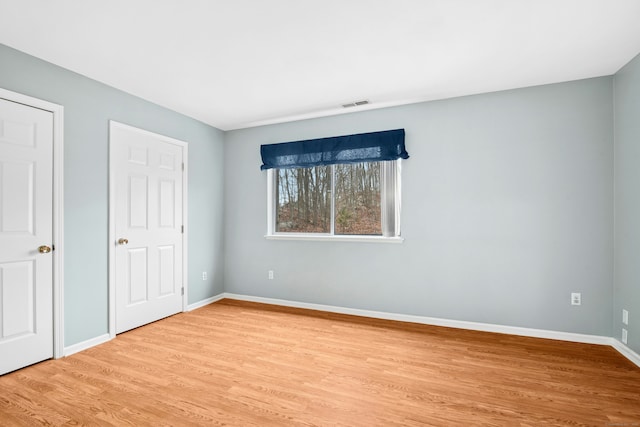 unfurnished bedroom featuring baseboards, visible vents, and light wood finished floors