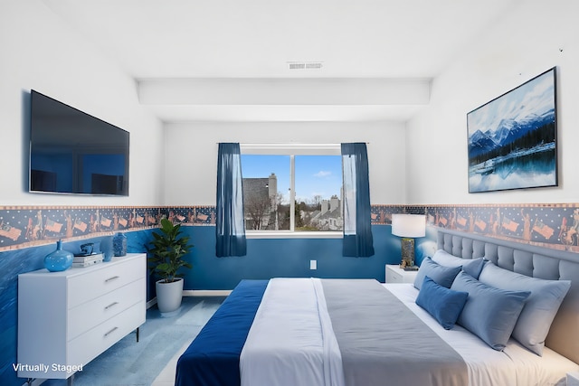 carpeted bedroom featuring a wainscoted wall and visible vents