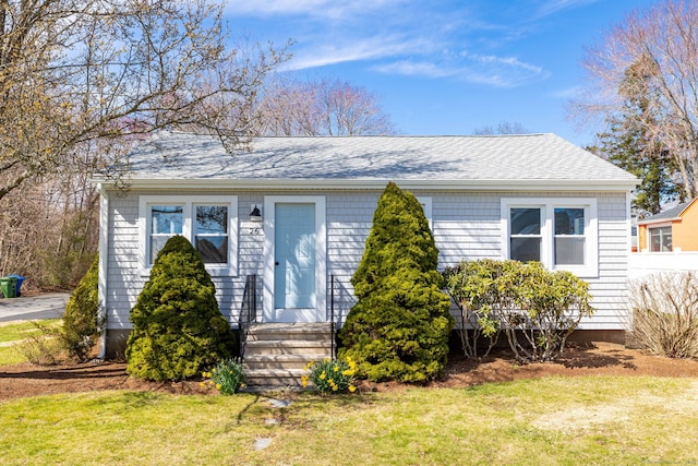 view of front of house featuring a front lawn, fence, and a shingled roof