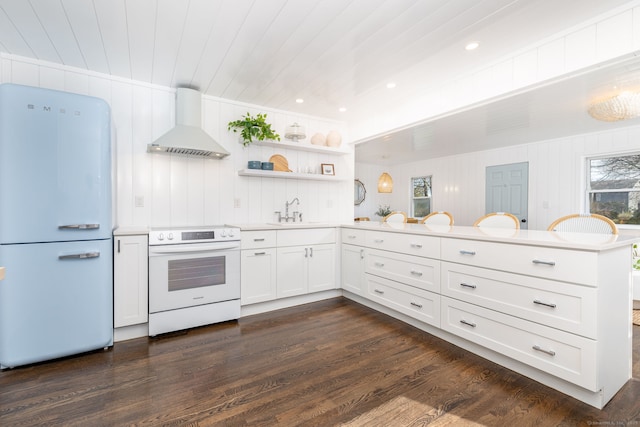 kitchen featuring dark wood finished floors, a peninsula, white appliances, wall chimney exhaust hood, and a sink