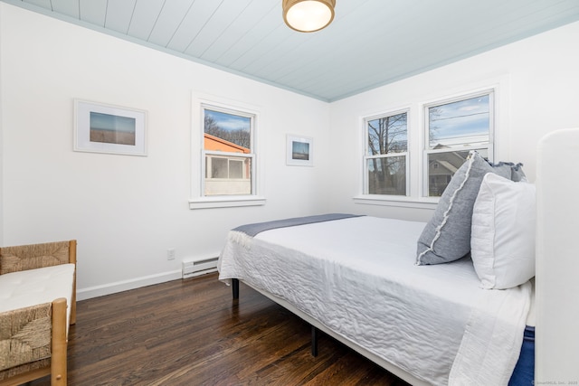 bedroom with multiple windows, wood finished floors, baseboards, and baseboard heating