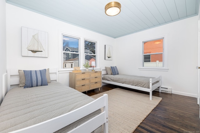 bedroom with a baseboard radiator, multiple windows, baseboards, and dark wood-style floors