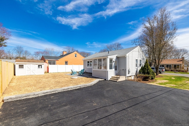 view of front of home featuring entry steps, an outdoor structure, a storage unit, and a fenced backyard