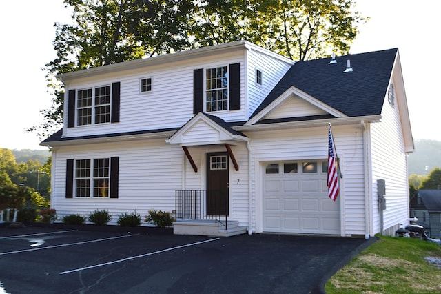 view of front facade with a garage and a shingled roof