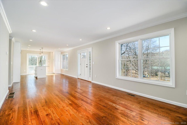 unfurnished living room featuring wood finished floors, visible vents, and crown molding