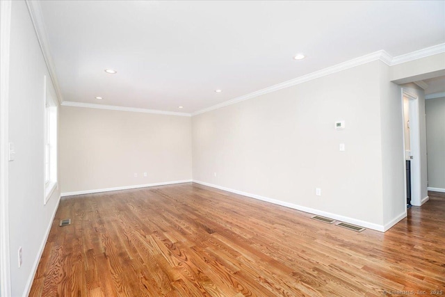 spare room with crown molding, baseboards, visible vents, and light wood-style floors