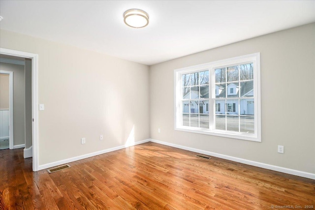 unfurnished room featuring visible vents, baseboards, and wood finished floors