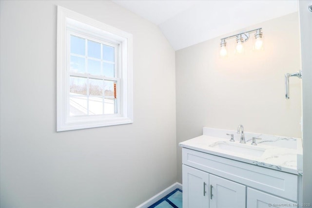 bathroom with lofted ceiling, vanity, and baseboards