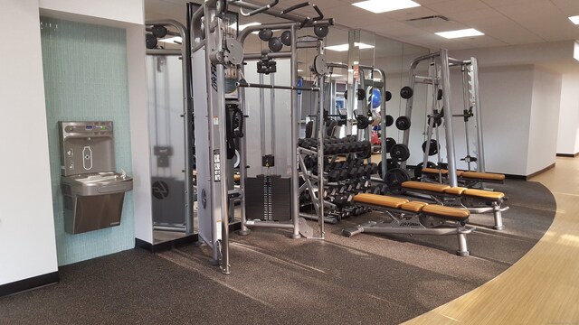 exercise room featuring baseboards and a drop ceiling