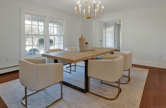 dining area with an inviting chandelier, ornamental molding, a baseboard heating unit, wood finished floors, and baseboards