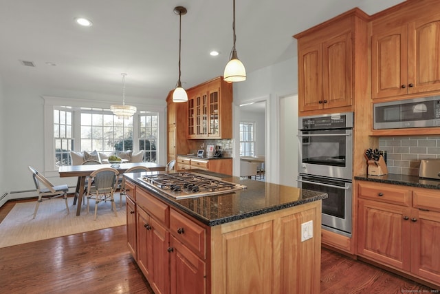 kitchen featuring appliances with stainless steel finishes, glass insert cabinets, a kitchen island, and dark wood-style floors