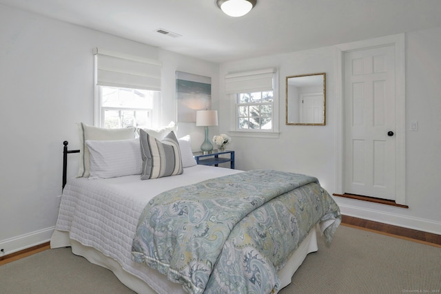 bedroom featuring baseboards, visible vents, and wood finished floors